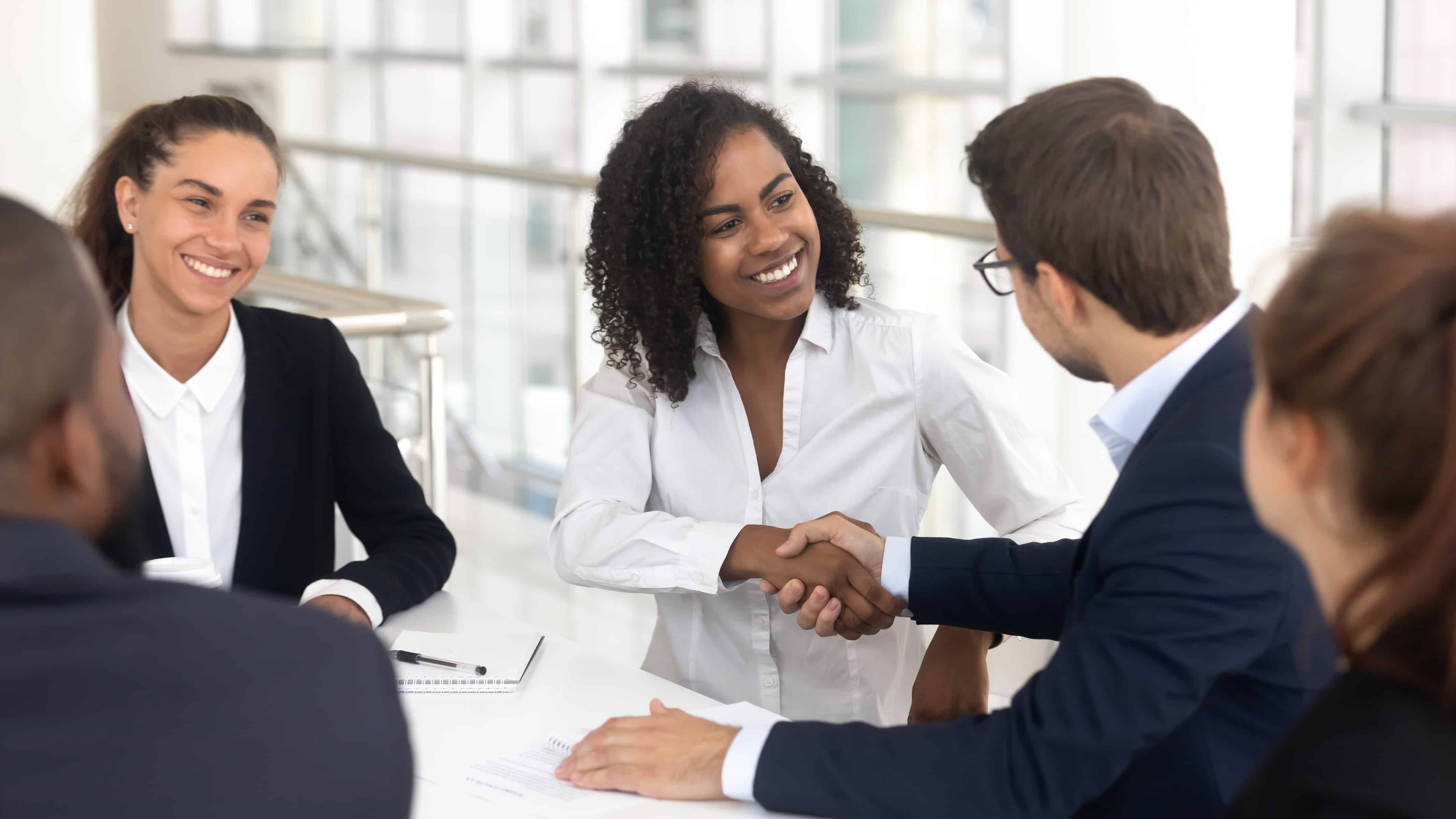 Professional team meeting - diverse business professionals shaking hands in modern office